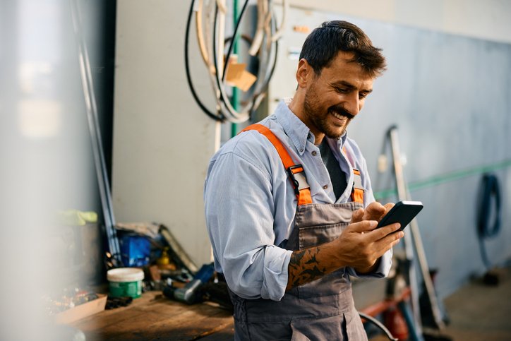 Car mechanic looking at his website on his phone