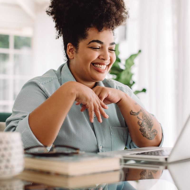 Positive woman video calling using laptop. Businesswoman teleconferencing on laptop while working from home.